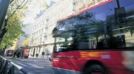 Vista de un autobús urbano en movimiento junto a una señal de prohibido estacionar sobre el fondo de altos edificios residenciales