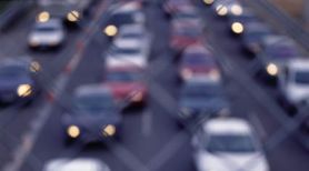 Imagen de un atasco de cuatro filas de coches visto desde un puente de una autopista atardeciendo