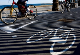 Vista de bicicletas circulando junto al mar sobre pavimento con señales de ceda el paso y una bicicleta