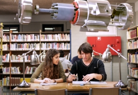 Energía 3D. documental sobre el valor de la energía. Alex con María en la biblioteca, sobre sus cabezas aparece un motor de un coche eléctrico
