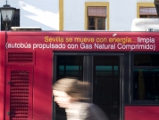Movilidad urbana. Vista de un autobús propulsado por gas natural circulando por la ciudad y una persona en bicicleta
