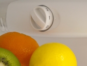 Equipos eficientes en el hogar. Vista del programador de temperatura interior de un frigorífico, vemos también un limón, una naranja y un kiwi.