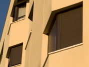 Edificación. Vista en primer plano de tres ventanas con persianas de un edificio