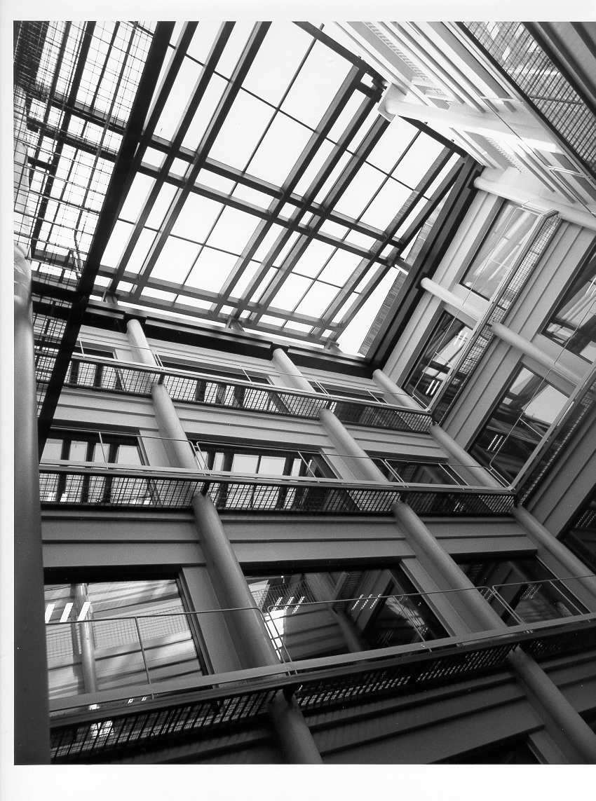 Vista desde abajo del interior de un patio de luces acristalado de un edificio moderno de estructura metálica blanca