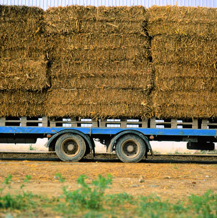 Vista lateral en primer plano de un remolque cargado con alpacas de paja apiladas en cuatro alturas