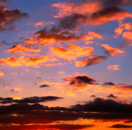 Imagen de un cielo rojizo al atardecer con un gran bloque de nubes