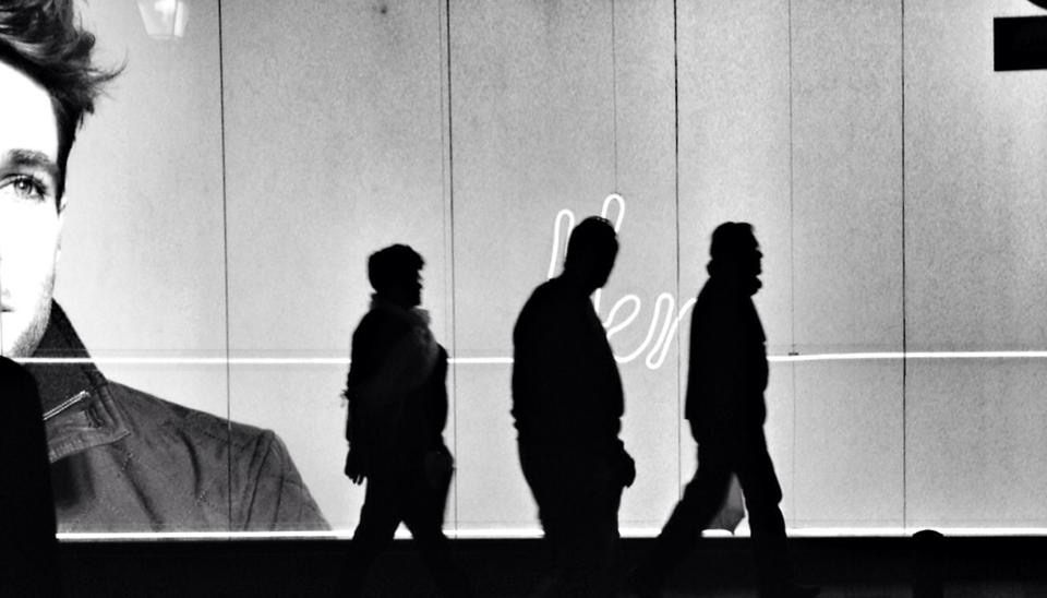 Tres personas caminando delante del escaparate de una tienda en la ciudad